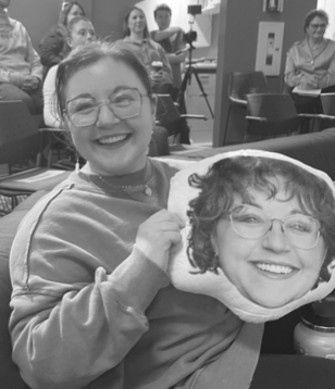 A person smiling while holding a pillow with a print of their own face on it